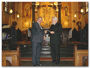 De voorzitter van de diocesane NSGV overhandigt de cd ‘Haarlemmer Orgelboek’ aan bisschop Punt.