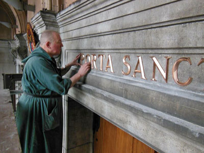 Broeder Leo Disch brengt de letters aan boven de H. Deur van de Nicolaasbasiliek in Amsterdam
