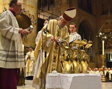 Mgr. Punt vult de kannen met olin tijdens de chrismamis