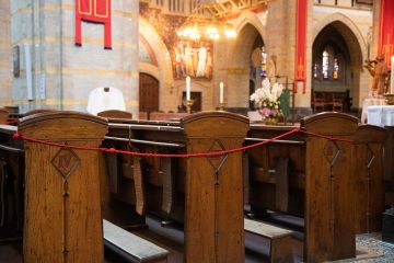 Kerkbanken zijn met rood koord afgezet om de anderhalve meter afstand te waarborgen